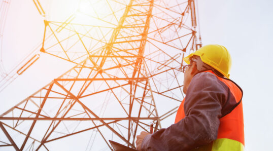 man looking at transmission tower as he evaluates sustainability of insulator