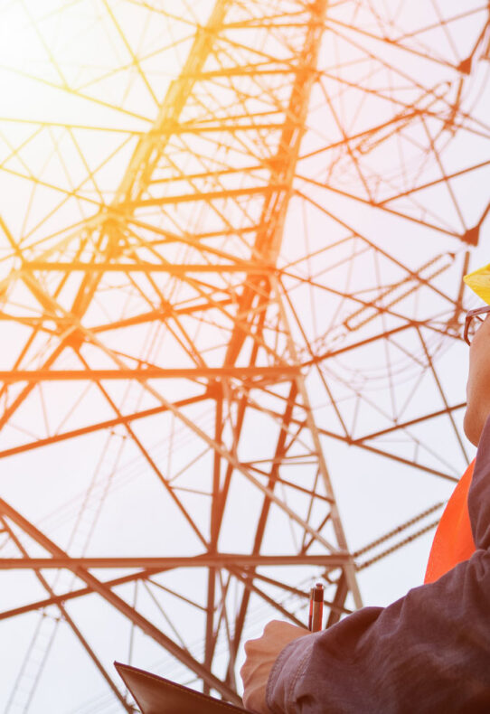 man looking at transmission tower as he evaluates sustainability of insulator