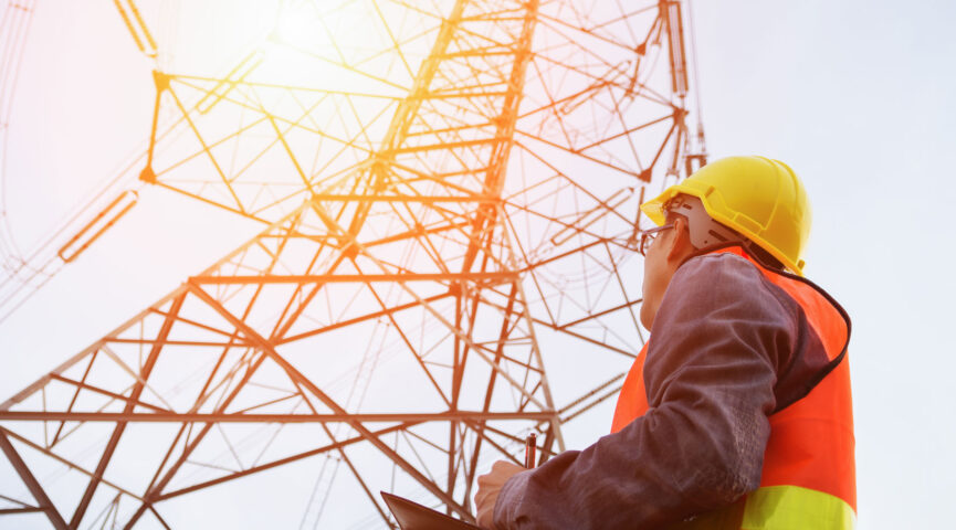 man looking at transmission tower as he evaluates sustainability of insulator